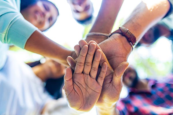 A group of people place their hands on top of each other.